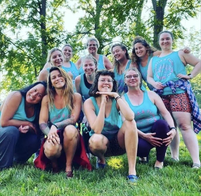 A group of women outdoors wearing light blue and posing for the camera.